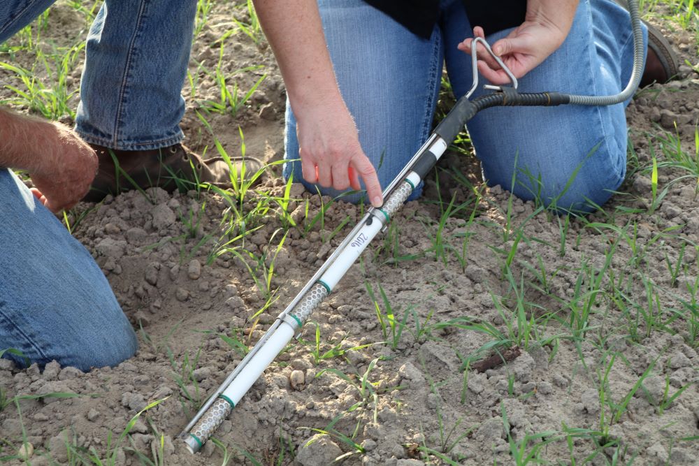 Agricultural Water Efficiency Team member holds soil moisture sensor in field.