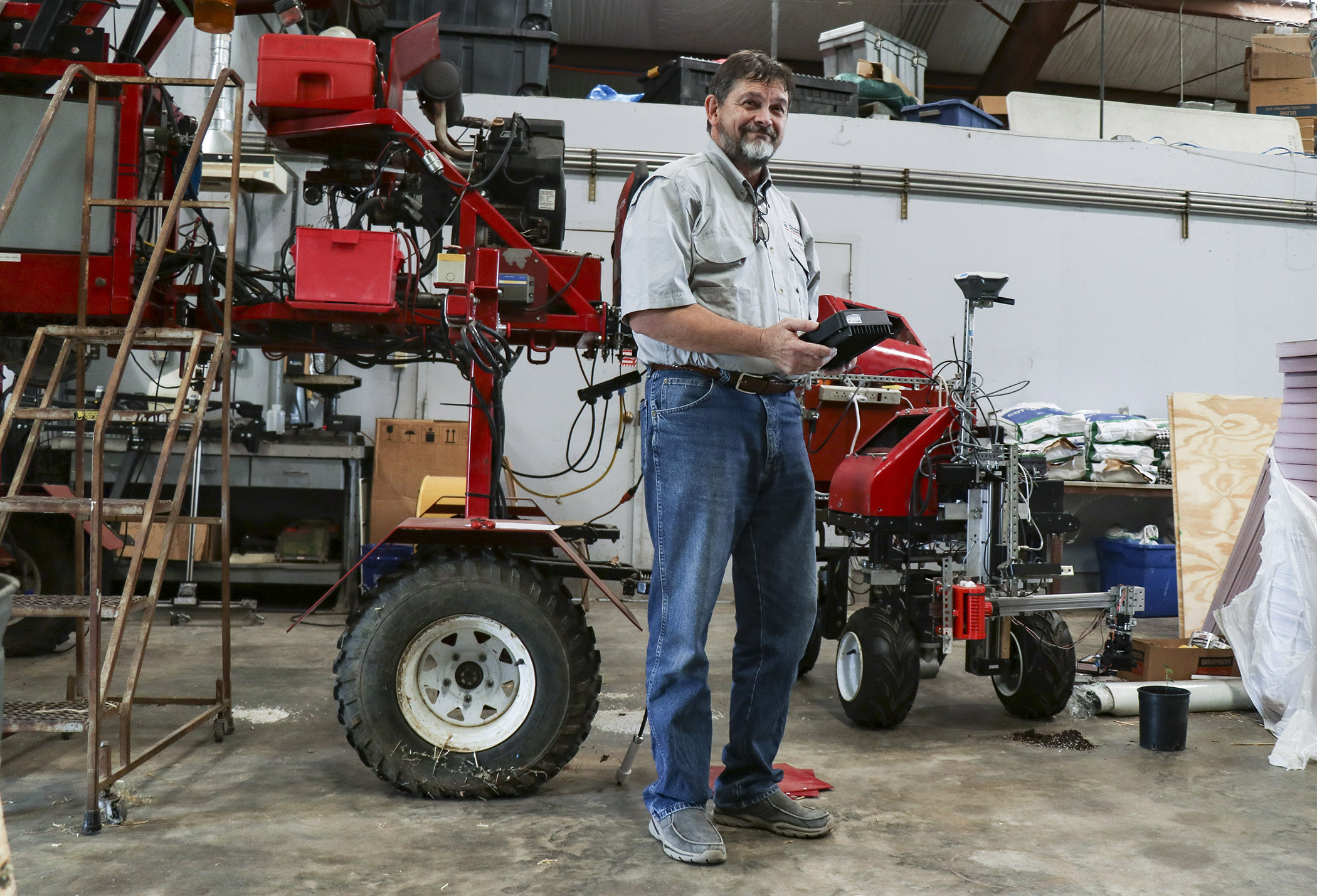 CAES professor Glen Rains holds the control panel to the “Little Red Rover.” The rover is a multipurpose robotic tool that can be used for planting, weed and pest management, and more. The robotic arm’s prototype camera is monitoring a small cotton plant. (Katie Walker)